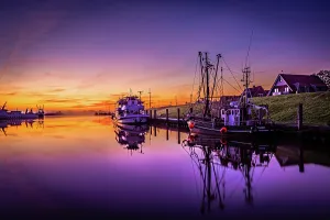 Shortly in front of sunrise in the harbour of Greetsiel with the anchored ships and reflection in the water, Greetsiel, Lower Saxony, Germany, Europe