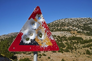 Shot triangular warning sign, large bullet holes