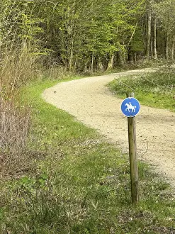 Sign for riders in front of designated signposted bridle path with soft sandy ground leading through mixed forest