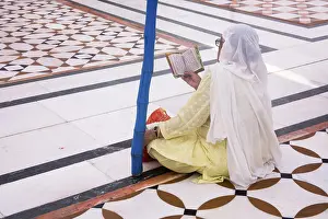 Sikh woman praying sitting on the floral structure pattern of the white marble inside Swarn Mandir Golden temple