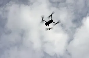 Silhouette of a drone in flight backlit against the sky