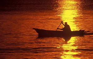 Silhouette of a fisherman in his boat at sunrise near Mikadi Beach