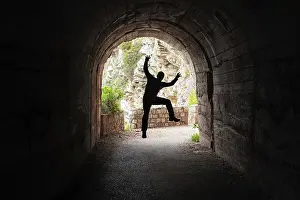 Silhouette of a man jumping in a dark tunnel on the walking path in Petrovac bay