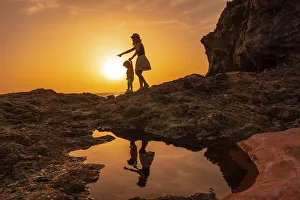 Silhouette of mother and son walking in the sunset on the beach of Tacoron in El Hierro