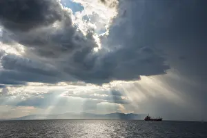 Silhouette of a ship, sun breaking through the clouds above the Amur in Vladivostok