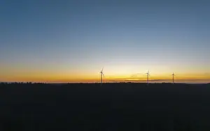 Silhouette of wind turbines in front of a colourful sunset sky