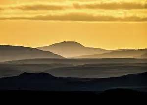 Silhouettes of mountains at sunset with yellow sky