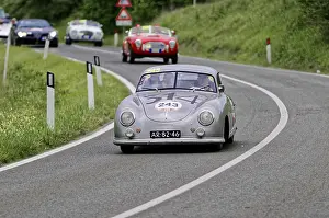 Silver-grey classic car with race number on a winding road