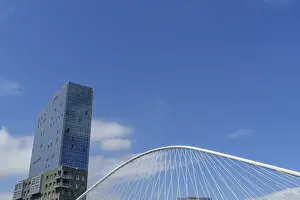 Single skyscraper, bridge, clouds in clear sky