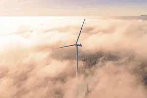 Single wind turbine rising from foggy sea