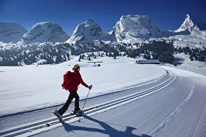 Ski tourer in a cross-country ski track climbing towards the Churfirsten under a clear blue sky