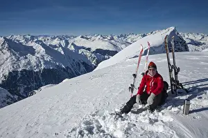 A ski tourer sits relaxed on the summit of the Tallihoren