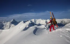 A ski tourer with skis on his rucksack