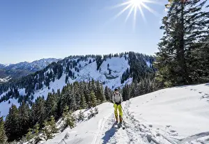 Ski tourer in wintry mountain landscape with sun star
