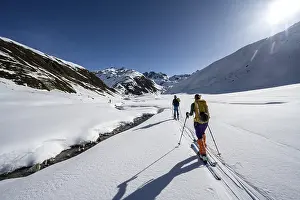 Two ski tourers in the snow by a mountain stream in the Funtauna Valley