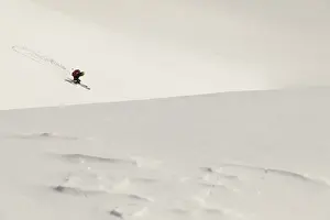 A skier descends a vast snow-covered mountain