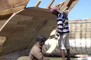 Two skilled labourers at work, inserting planks on the new dhow