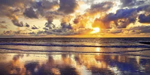 The sky with colourful clouds reflected in the mudflat landscape at sunset