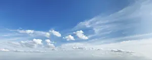 The sky displays a clear blue expanse adorned with soft white clouds