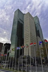 Skyscraper with international flags and cloudy sky
