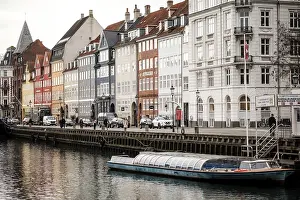 A small boat moored along a canal flanked by rows of colorful buildings in Nyhavn