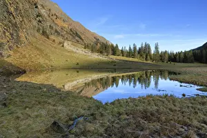 A small body of water reflects the surrounding mountains and trees
