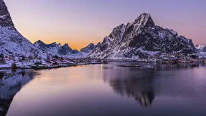 The small fishing village Reine on the Lofoten islands in Norway in winter with steep snowcapped mountains