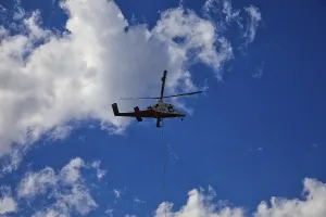 Small helicopter in the blue sky with few clouds