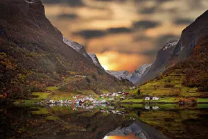 Small homes on the shore of a fjord photographed from a Fjords sightseeing cruise boat leaving Flam in autumn