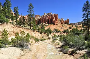 A small river flows through a landscape of distinctive rock formations and forest