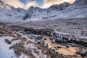 Small river in snowy landscape with winter Cullins mountains in the background