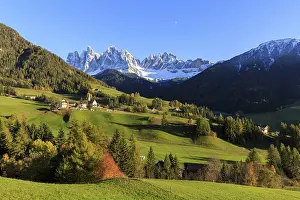 A small settlement nestled in an autumnal meadow landscape with a panoramic view of the Dolomites