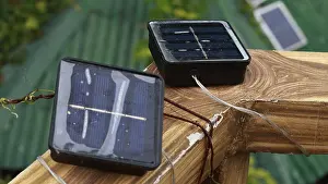 Small solar panels on a wooden surface with cables