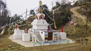 Small stupa with colorful prayer flags on a hill