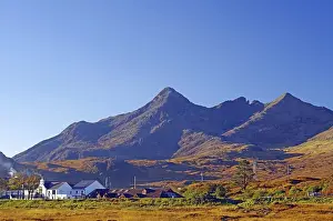 Category Mountain Landscapes Prints: A small village lies against an impressive mountain backdrop under a clear blue sky