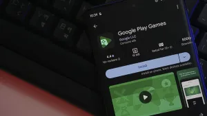 Smartphone displaying Google Play Games app installation page with a keyboard backdrop