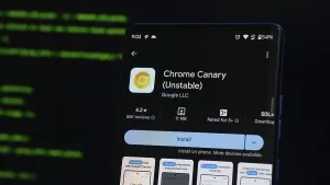 Smartphone showing Chrome Canary app on Google Play with code-like screen reflection in the background