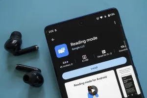 A smartphone showing the Reading mode app by Google ready to install with earbuds beside it