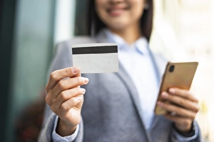 Smiley businesswoman with smartphone credit card outdoors