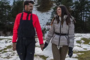 Smiling young couple enjoying a winter walk in the snowy mountains