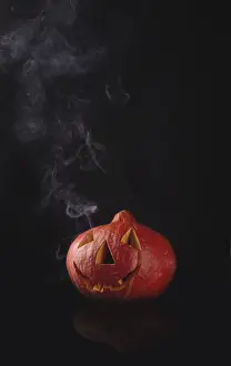 Smoke streams from a pumpkin on black glass