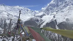 Snow-capped Himalayan mountains with waving prayer flags in the foreground