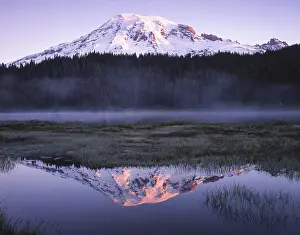 Snow capped mountain reflecting in a calm lake at dusk
