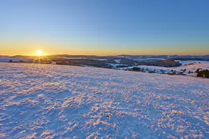 Snow-covered landscape at sunrise lying gently over the hills