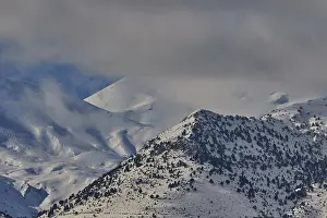 Snow-covered mountain range under a cloudy sky