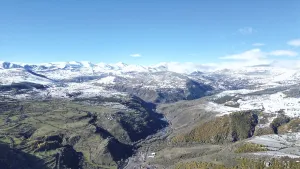 Snow-covered mountain range with a winding river and clear sky viewed from above