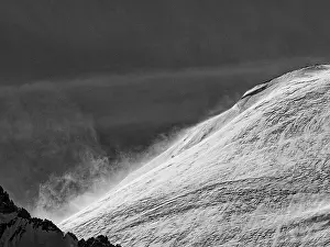 A snow-covered mountain in stormy conditions captured in a black and white image