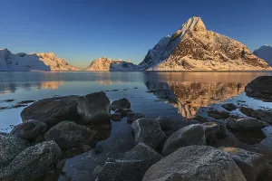 Snow-covered mountains reflected in the fjord at sunrise