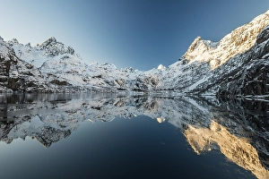 Snow covered mountains reflecting in the Trollfjord