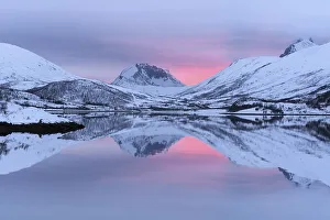 Snow-covered peaks in the evening light reflected in the lake